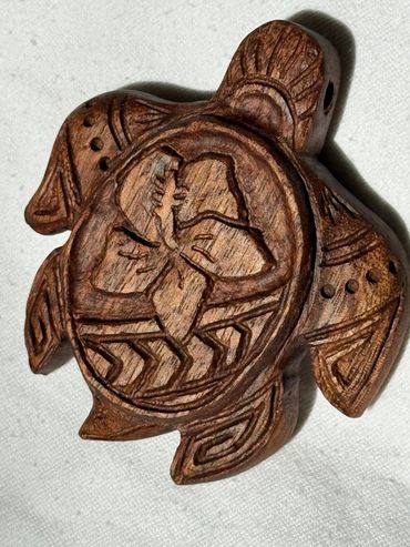 Intricately carved wooden turtle with floral and geometric designs.