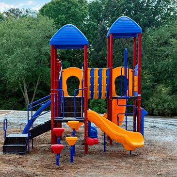 Colorful playground structure with slides and climbing features in a park.