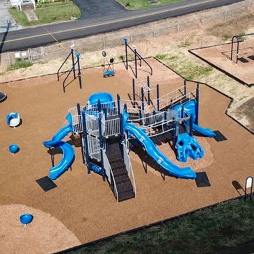 A modern playground with blue slides and climbing structures.