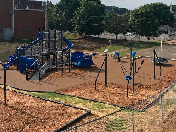 Modern playground with slides, swings, and climbing structures in an outdoor schoolyard.
