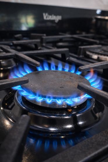 Blue flames burning on a gas stove burner in a kitchen.