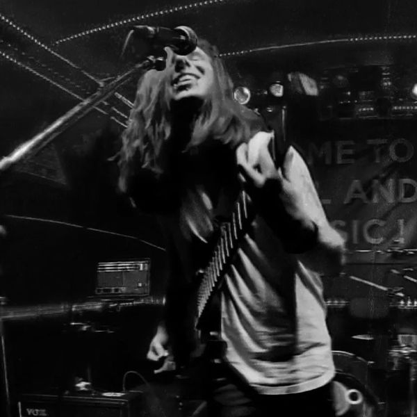 Guitarist passionately performing on stage under vibrant lights.