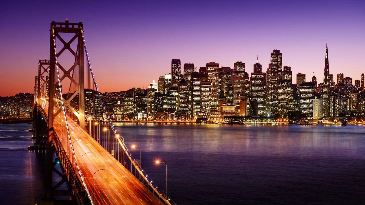 San Francisco skyline at dusk with the illuminated Bay Bridge.