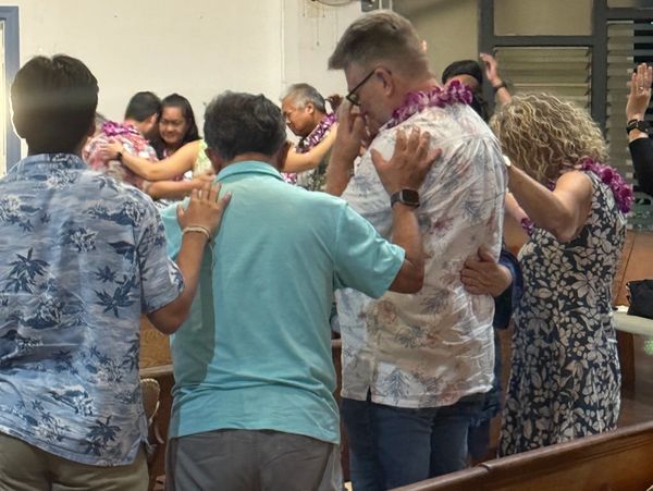 People praying together with hands on each other's shoulders.