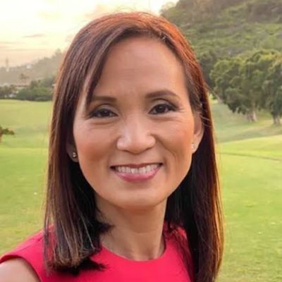 Woman smiling outdoors in a red top.