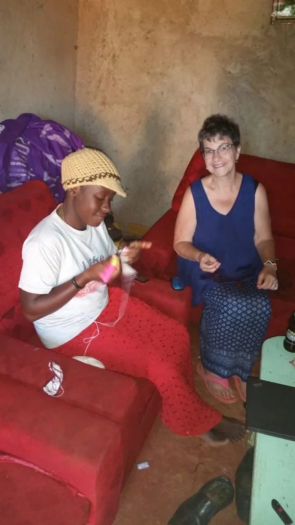 Two women sitting and smiling in a cozy room with red sofas.