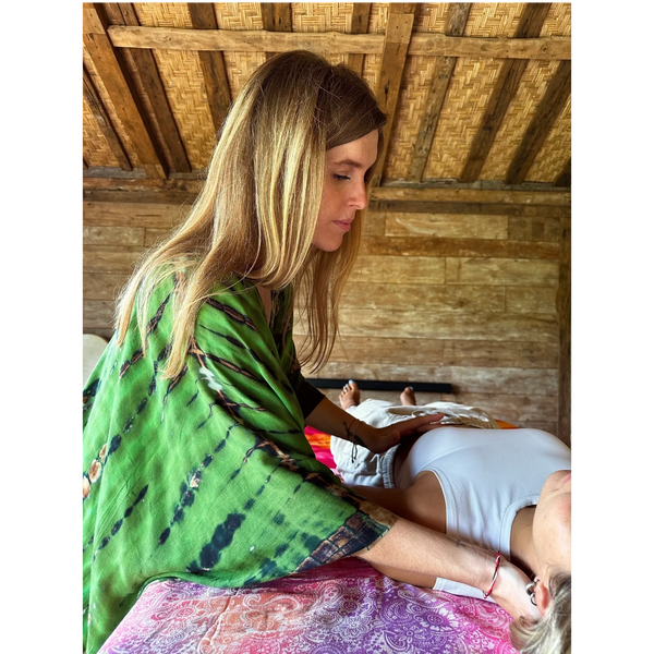 A woman in a green shawl giving a massage to a person lying down.