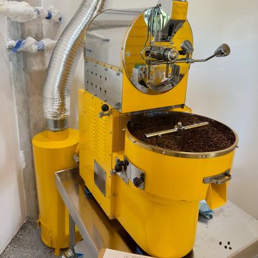 Yellow coffee roasting machine with freshly roasted beans.