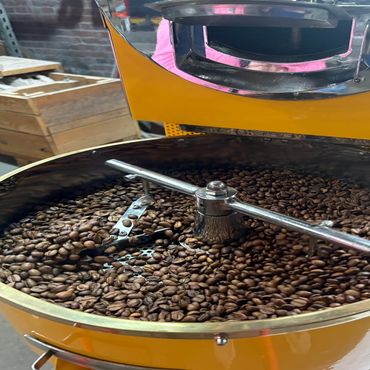 Close-up of roasted coffee beans cooling in a yellow coffee roaster.