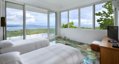 Modern bedroom with glass walls and nature views.
