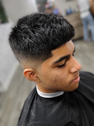 Fresh fade haircut with textured top and sharp edges.