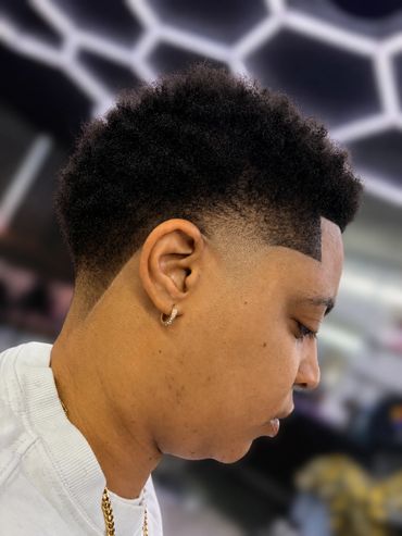 Close-up of a man with a fresh fade haircut and gold earring.
