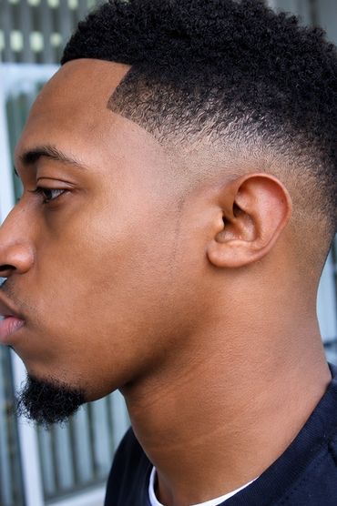Profile of a man with a fresh fade haircut and goatee beard.