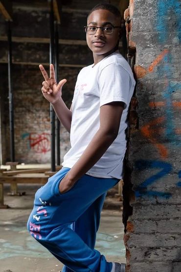 Young man leaning against a graffiti-covered wall making a hand gesture.