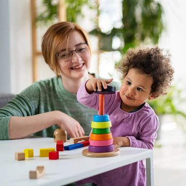 Resources for Speech Language Pathologists. A toddler stacking colorful rings with a caregiver.