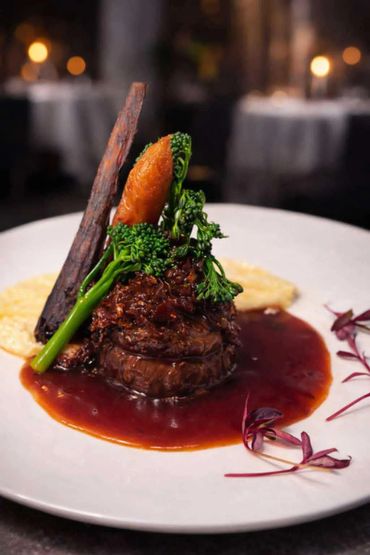 Gourmet steak with broccolini and rich sauce on a white plate.