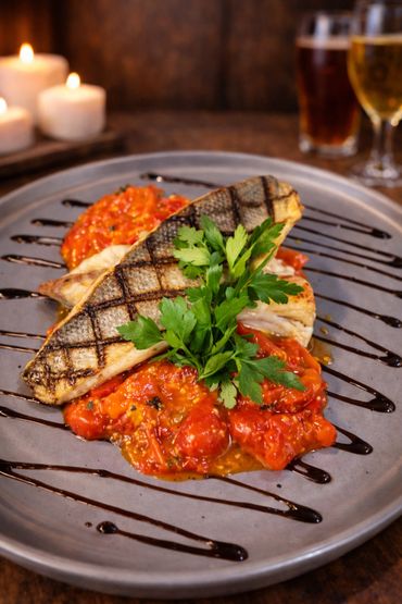 Grilled fish fillet with tomato sauce and parsley garnish on a gray plate.