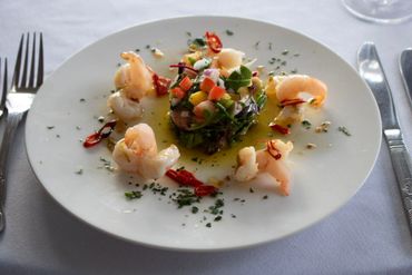 Elegant shrimp salad with leafy greens and diced vegetables on a white plate.