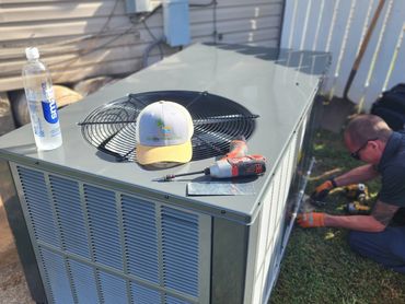 A HVAC installer placing a new unit at a house.