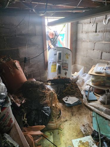 A technician removing a water heater from a crawl space.