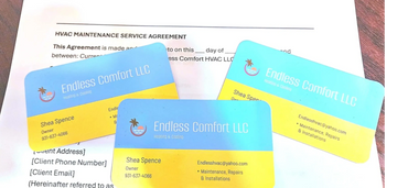 blue and yellow endless comfort HVAC business cards sitting on top of an annual maintenance contract