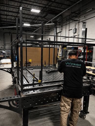 Employee assembling a metal suspended bar frame in a fabrication shop.