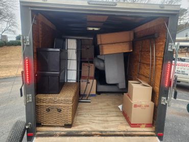 Packed moving trailer with furniture and boxes ready for transport.