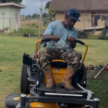 Man riding a yellow lawn mower in a yard.