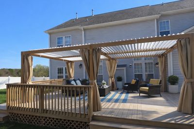 A spacious backyard deck with a pergola and outdoor seating under clear skies.