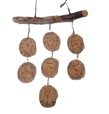 Wooden wind chime with engraved tree designs and the words 'Madrone Song'.