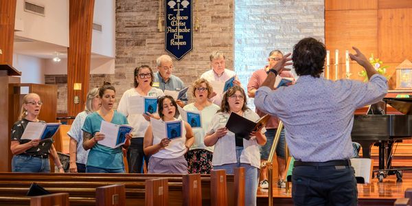 Choir singing under conductor's guidance in a church.