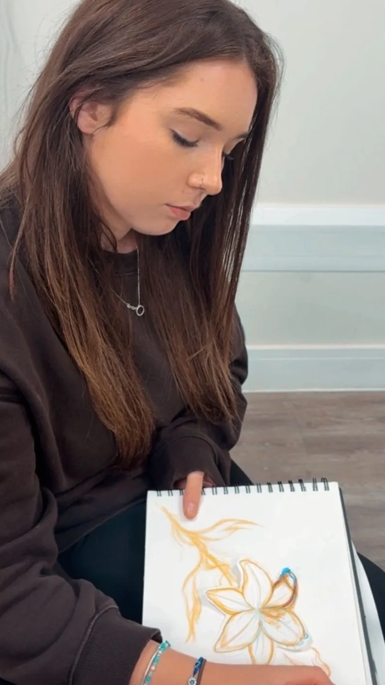 Young woman sketching a flower on paper.
