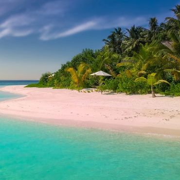Serene tropical beach with clear turquoise water and lush greenery.