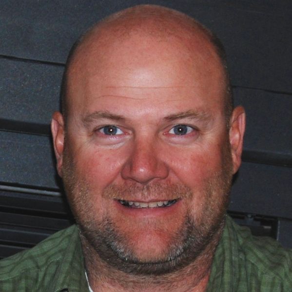 Smiling middle-aged man with a bald head and beard.