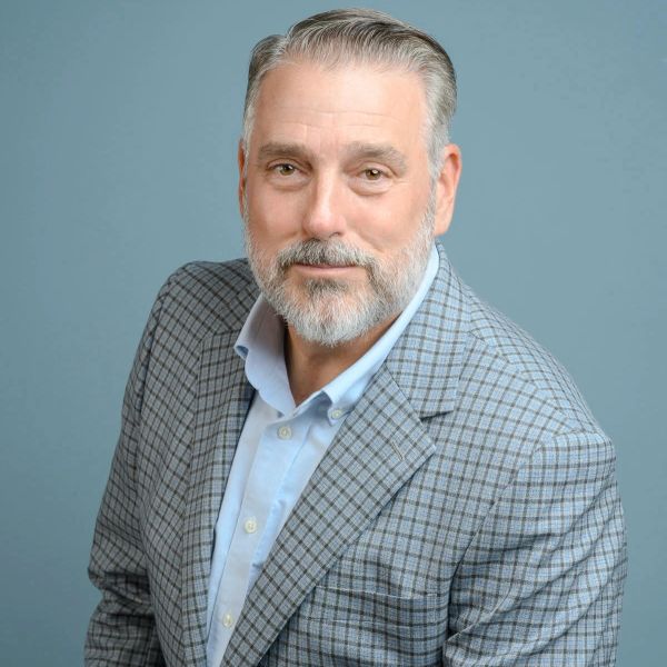 Middle-aged man with a beard wearing a plaid jacket.
