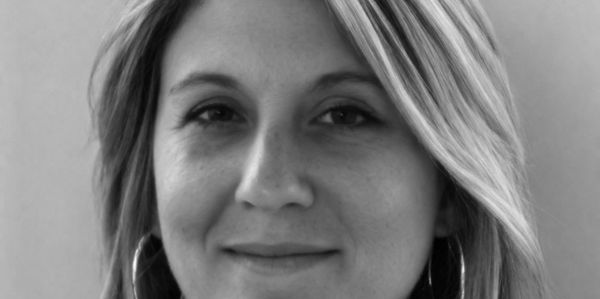 Black and white close-up portrait of a smiling woman with hoop earrings.