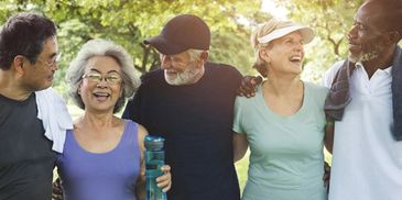 Diverse group of seniors enjoying a walk outdoors, smiling and close together.