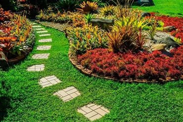 Curved garden path with vibrant plants and green grass.