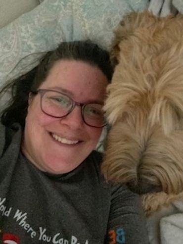 Smiling woman lying next to a large, fluffy dog.