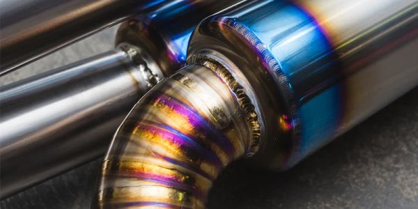 Close-up of a colorful, heat-treated metal exhaust pipe.