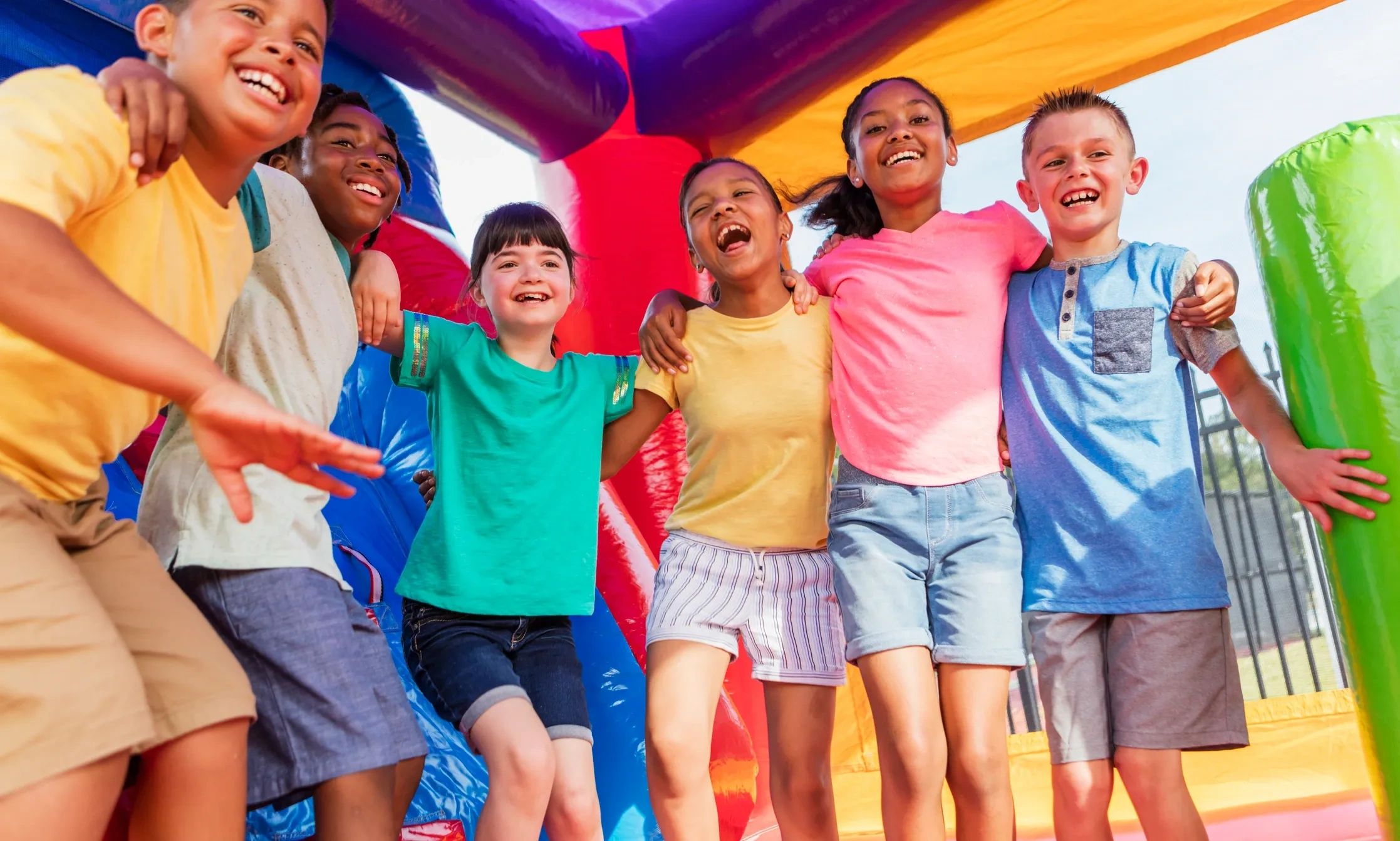 Group of happy kids having fun in a colorful inflatable bounce house.