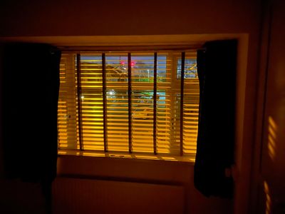 Window with blinds partially open, illuminated by warm light.