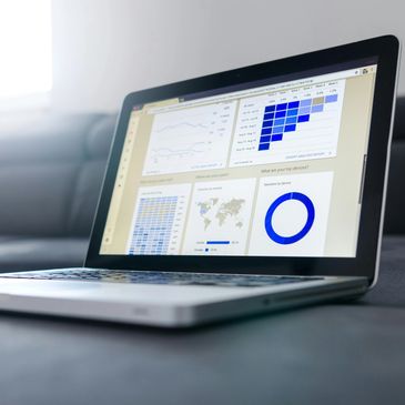 Laptop displaying analytical reports and charts on a gray couch.