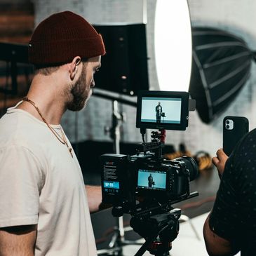 Two men working with a professional video camera and smartphone in a studio setup.