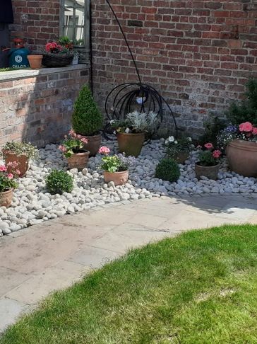 A corner of a garden with flower pots on white stones