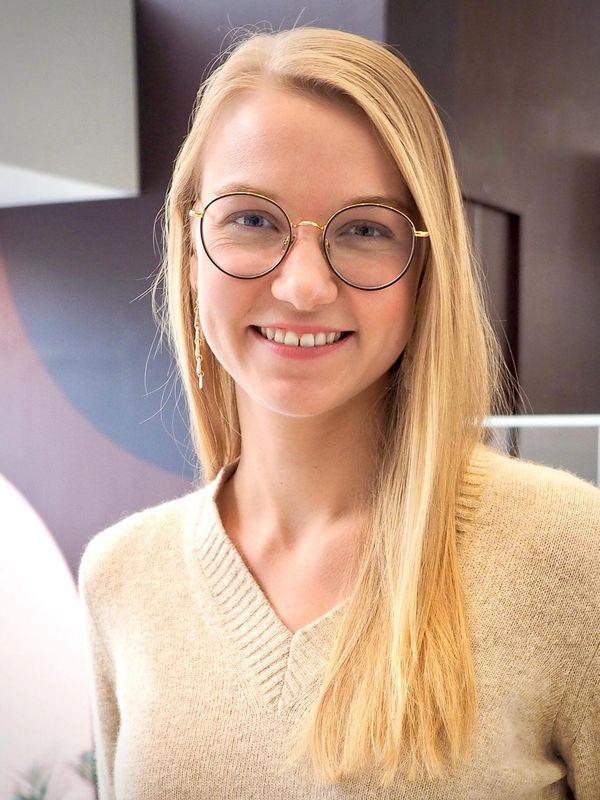 Junge Frau mit Brille und langem blonden Haar lächelt.
