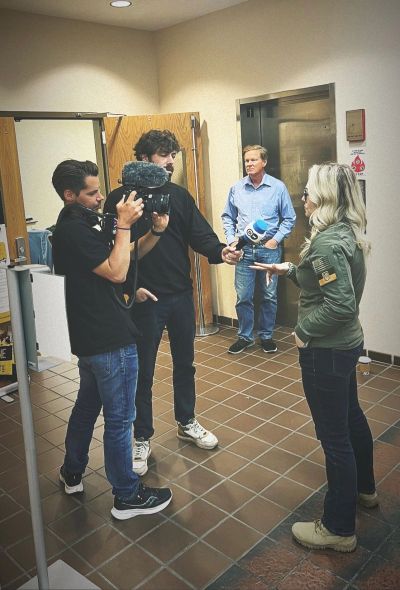 A woman being interviewed by a news crew indoors.