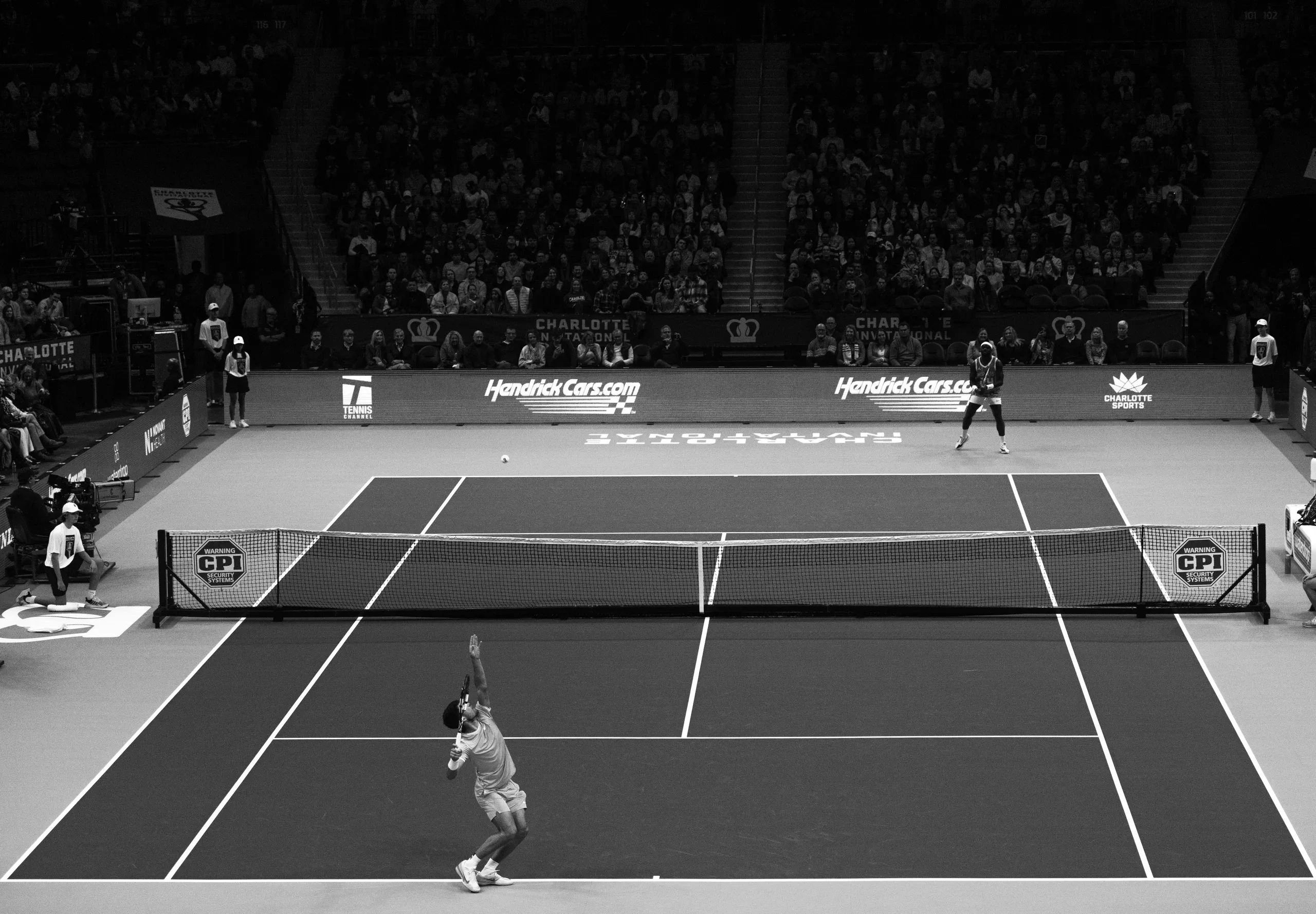 Black and White image of Carlos Alcaraz serving Frances Tiafoe at the Charlotte Invitational.