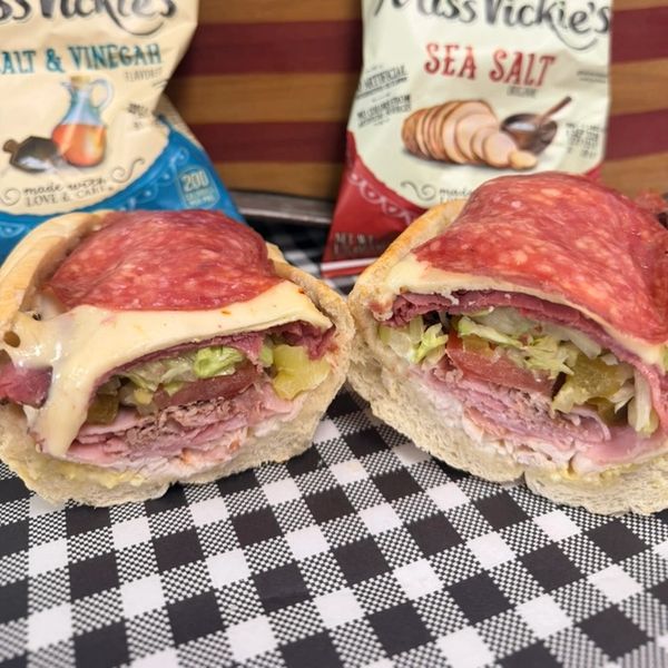 Italian sub sandwich with meat, cheese, and veggies, served with chips.