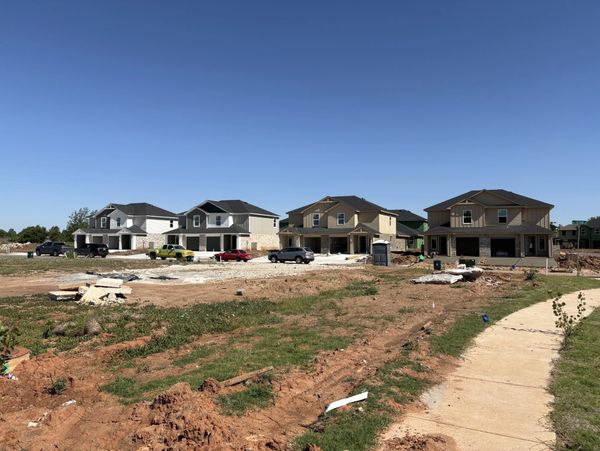 Row of newly built houses under construction with clear blue sky.